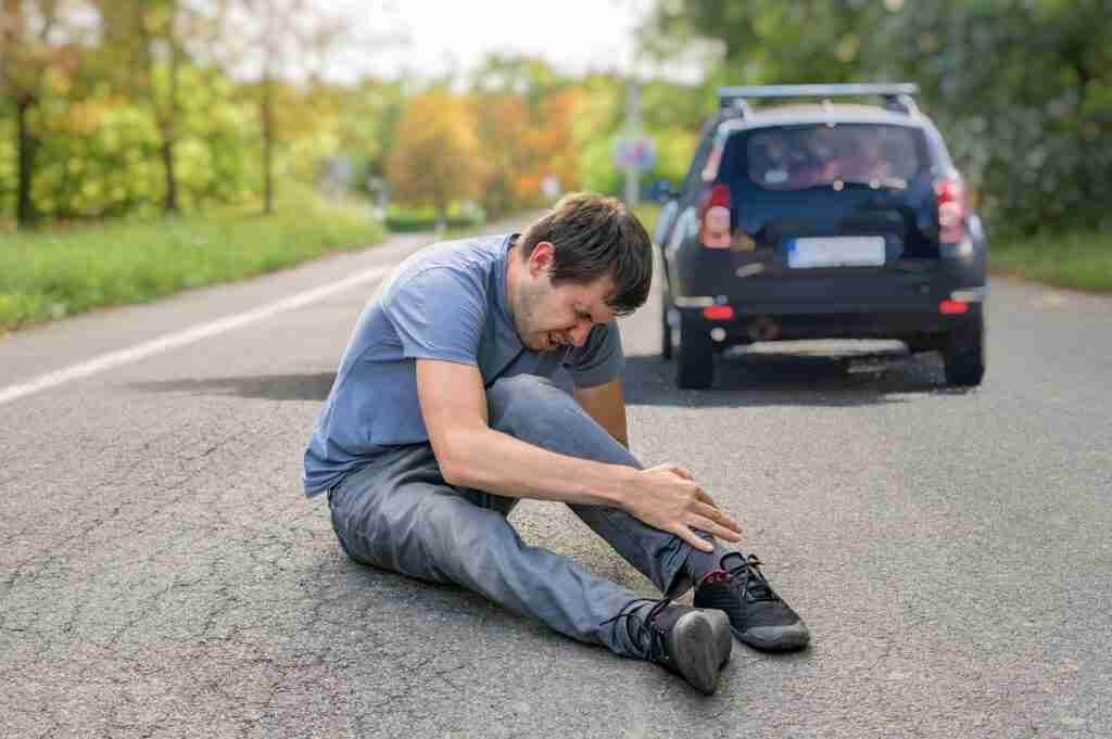 Hit And Run Concept. Injured Man On Road In Front Of A Car.