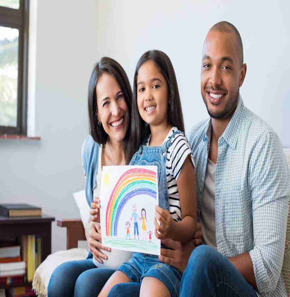Smiling daughter showing painting of family with parents and beautiful rainbow. Happy child showing