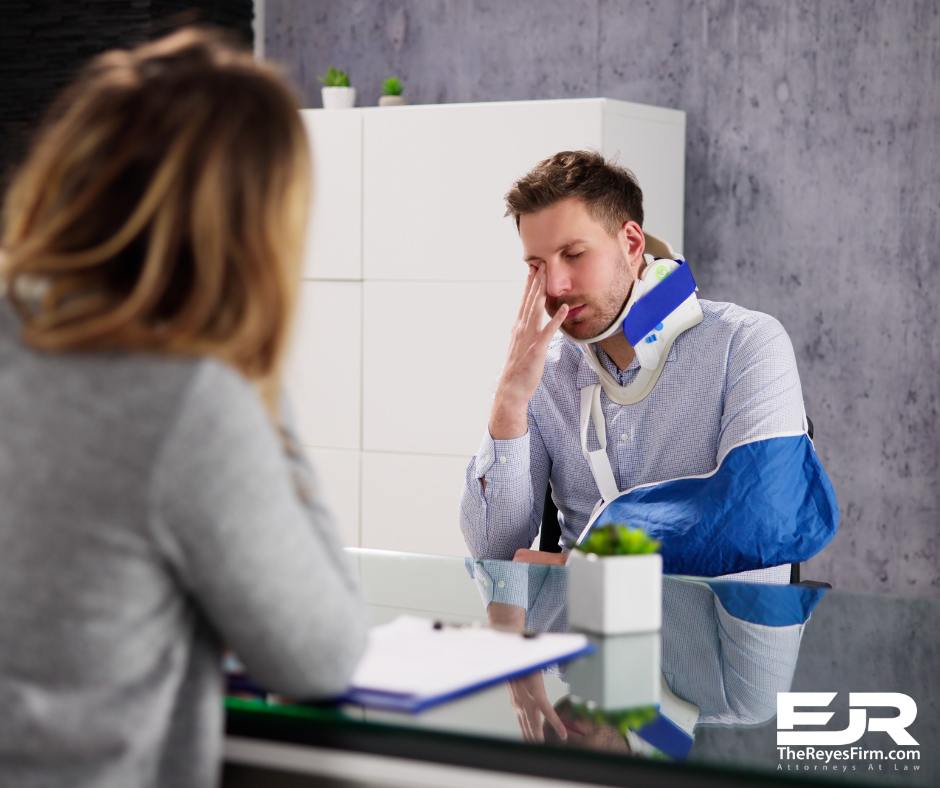 Man with neck brace and arm sling discussing his personal injury claim with a lawyer at The Reyes Firm.
