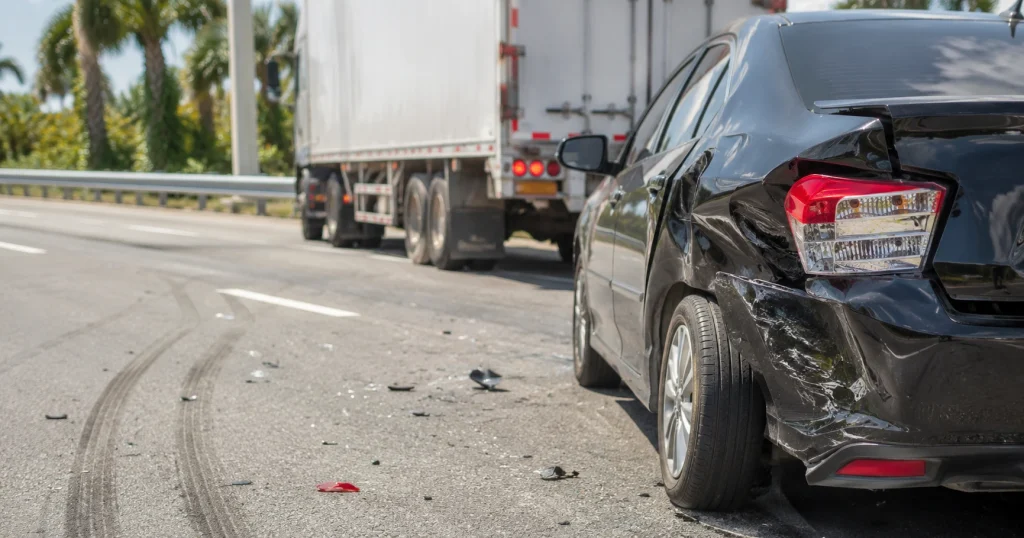 Auto dañado después de un accidente con un camión comercial en una carretera de Florida, con escombros y marcas de frenado en el pavimento, for illustrative purposes only.
