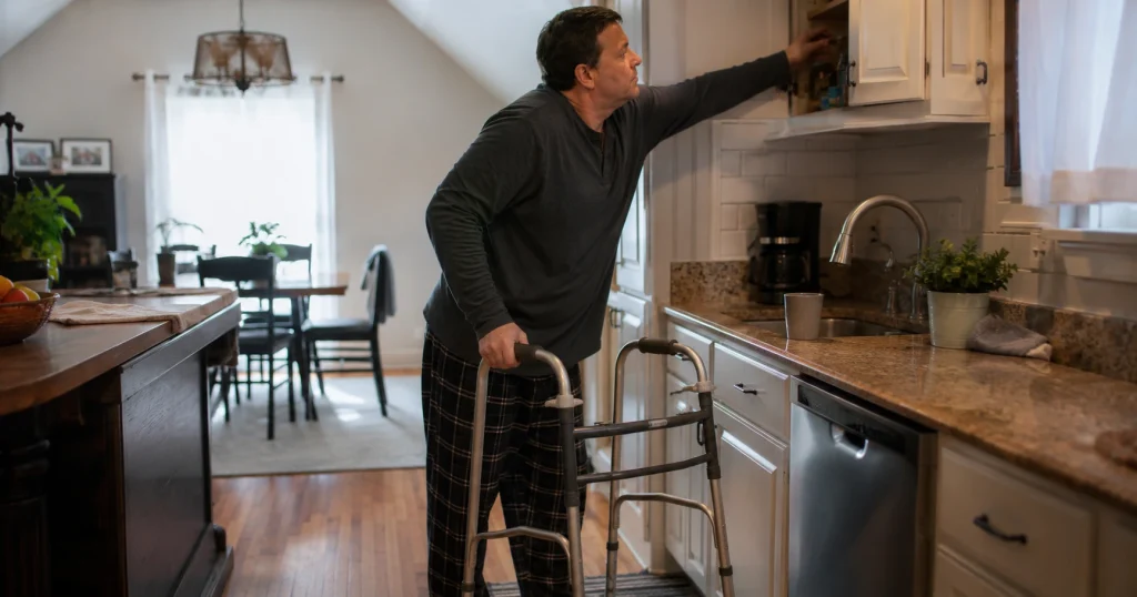 Person with limited mobility using a walker while doing a daily task at home after a catastrophic injury, for illustrative purposes only.